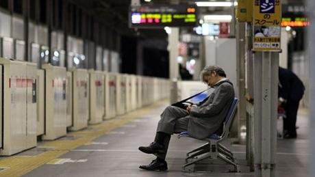 Người lao động ngồi chờ tàu đêm ở Nhật Bản. Ảnh: BBC